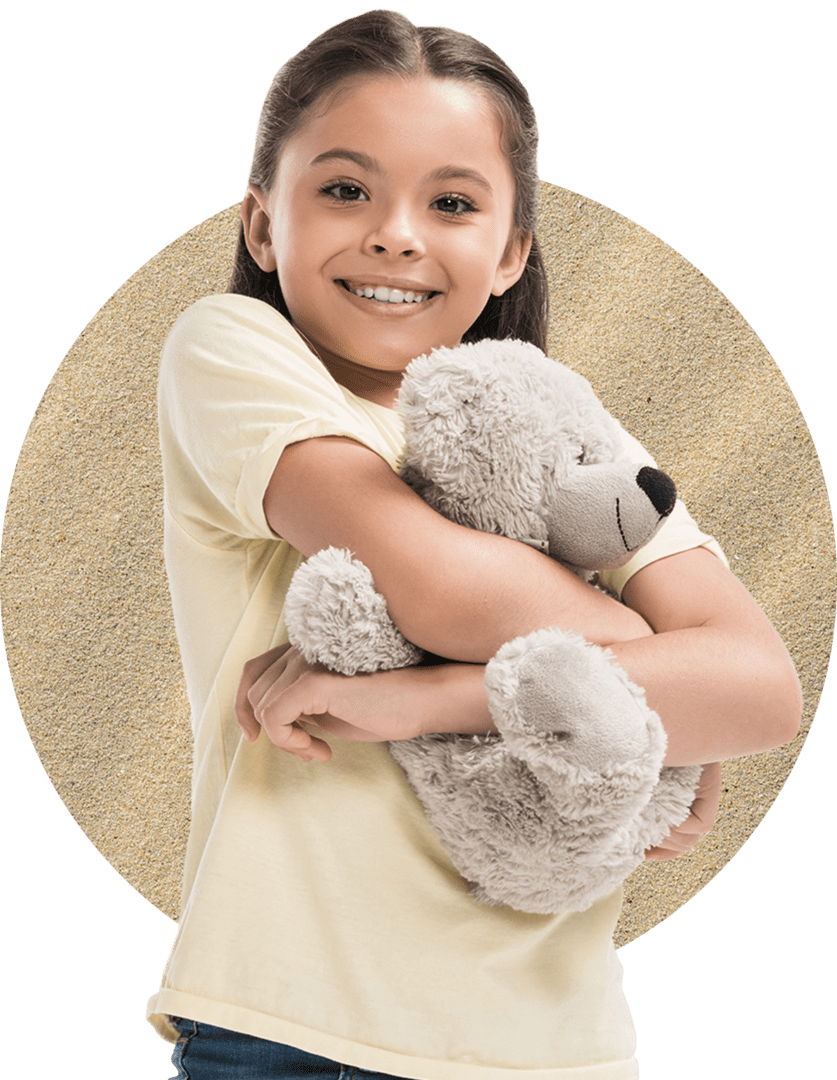 A smiling girl in a yellow shirt hugs a gray teddy bear against a textured circular background.