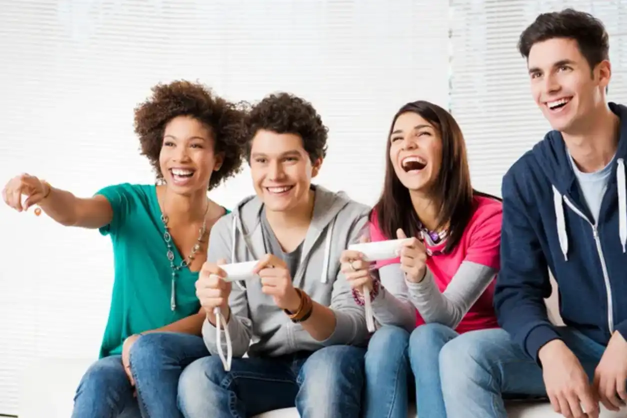 Three friends excitedly playing video games together on a couch.