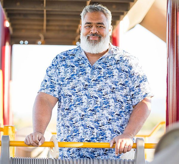 Smiling man pushing a shopping cart in a store aisle.