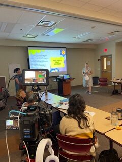 A presenter explains a topic to an attentive audience in a classroom setting.