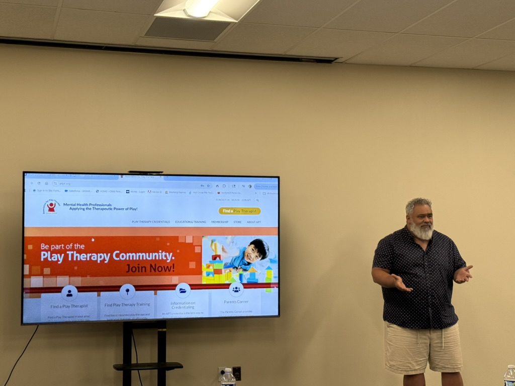 Man presenting in front of a screen about therapy community.