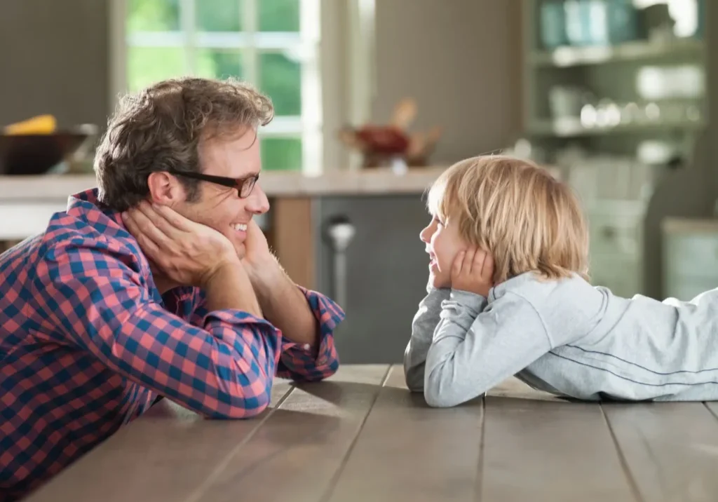 Father and son sharing a joyful moment at the table.