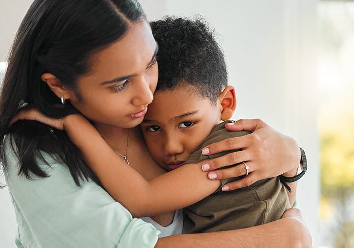 A woman comforting a sad child with a warm embrace.