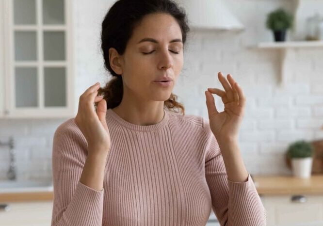 Woman meditating with eyes closed and hands in a mudra gesture.