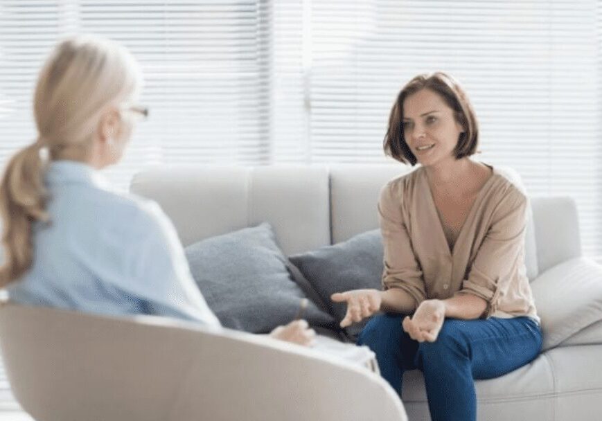 Two women engaged in a thoughtful conversation on a couch.