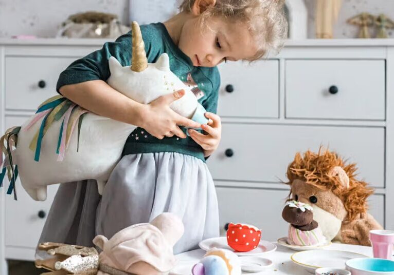 Child playing with a stuffed rabbit and toy hedgehog in a cozy room.